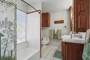 Bathroom featuring curtained shower, a bathtub, toilet, vanity, and tile patterned flooring