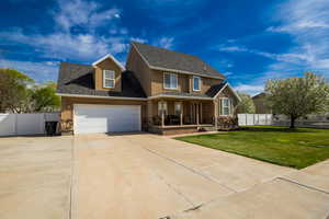 Traditional-style home featuring a porch, a front lawn, driveway, stone siding, and stucco siding