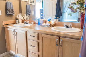 Full bathroom with double vanity, a sink, and a wealth of natural light