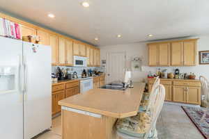 Kitchen with recessed lighting, a kitchen island with sink, white appliances, a sink, and light tile patterned flooring
