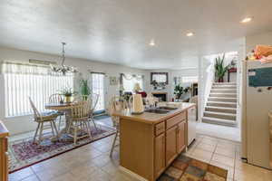 Kitchen featuring recessed lighting, white appliances, a kitchen island with sink, a fireplace, and a sink
