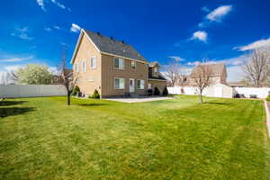Rear view of property with a patio, a storage unit, an outbuilding, a lawn, and a fenced backyard