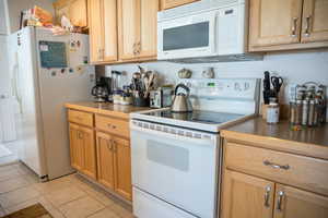 Kitchen featuring light tile patterned floors and white appliances