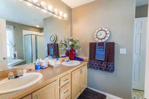 Full bath with a bath, a shower stall, double vanity, and a sink