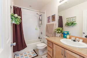 Bathroom with vanity, shower / bath combo with shower curtain, toilet, visible vents, and tile patterned flooring