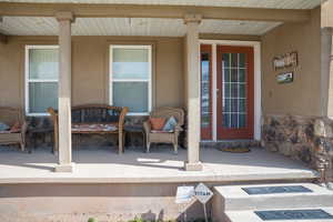 Doorway to property featuring stucco siding and covered porch