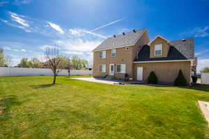 Back of house featuring a patio, roof with shingles, a yard, and fence