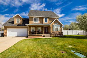 Traditional home with driveway, stucco siding, fence, a porch, and a front lawn