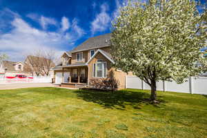 Back of property featuring fence, a lawn, stucco siding, and stone siding