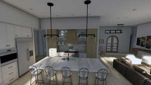 Kitchen with white appliances, white cabinets, custom range hood, and a sink