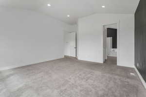 Unfurnished bedroom with vaulted ceiling, carpet, and baseboards
