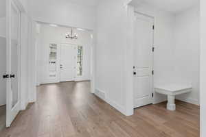 Entryway with visible vents, baseboards, a notable chandelier, and light wood-style floors