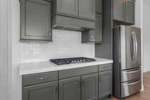 Kitchen with gray cabinetry, stainless steel appliances, light countertops, and backsplash