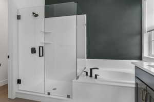 Bathroom featuring wood finished floors, a garden tub, vanity, and a stall shower