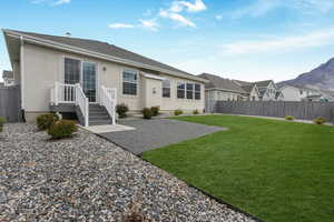 Back of property with a yard, stucco siding, a fenced backyard, and a patio area