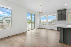 Unfurnished dining area with baseboards, a wealth of natural light, and an inviting chandelier