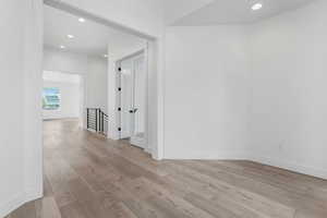 Interior space featuring baseboards, recessed lighting, an upstairs landing, and light wood-style flooring