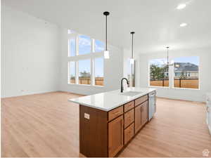 Kitchen with recessed lighting, light wood-style flooring, brown cabinets, dishwasher, and a sink
