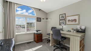 Office space with visible vents, vaulted ceiling, carpet, and a healthy amount of sunlight