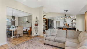 Living area with a chandelier, baseboards, wood finished floors, and lofted ceiling