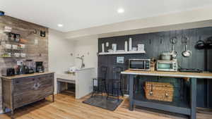 Bar featuring wood walls, wood finished floors, stainless steel microwave, and a toaster