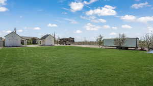View of yard with an outbuilding, a storage shed, and fence