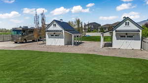View of jungle gym featuring fence, an outdoor structure, a yard, and a shed