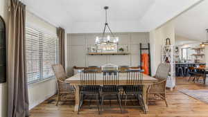 Dining space featuring wood finished floors, a chandelier, plenty of natural light, and vaulted ceiling