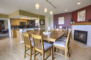 Dining area with a textured ceiling, a tiled fireplace, recessed lighting, and light wood finished floors