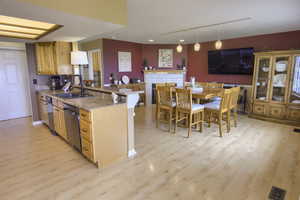 Kitchen with track lighting, light wood-style flooring, dishwasher, a sink, and a peninsula
