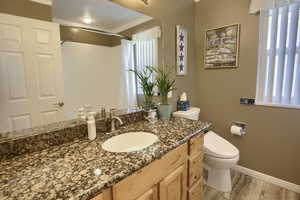Bathroom featuring baseboards, wood finished floors, a wealth of natural light, and toilet