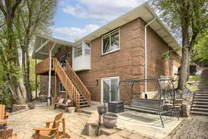 Rear view of property with a patio, stairs, and brick siding