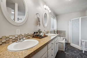 Bathroom with a shower stall, marble finish floor, backsplash, a sink, and a garden tub