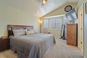 Bedroom with a textured ceiling, vaulted ceiling, carpet floors, and baseboards