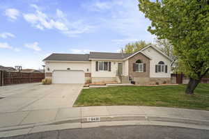 Ranch-style house featuring fence, a front yard, concrete driveway, and an attached garage