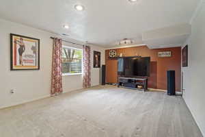 Living area featuring visible vents, ornamental molding, carpet flooring, and baseboards