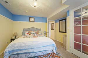 Bedroom with carpet flooring, a textured ceiling, visible vents, and baseboards