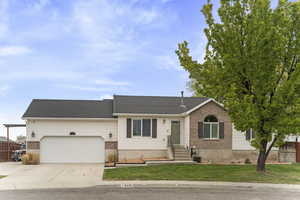 Ranch-style home with concrete driveway, an attached garage, fence, brick siding, and a front lawn