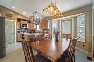 Dining room with baseboards, visible vents, an inviting chandelier, and vaulted ceiling