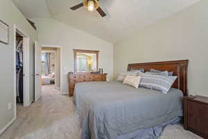 Bedroom with lofted ceiling, ceiling fan, a closet, light carpet, and a spacious closet