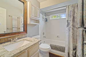 Full bathroom featuring shower / bath combo, vanity, toilet, and backsplash