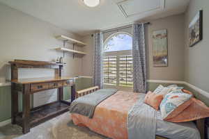 Carpeted bedroom with attic access and wainscoting