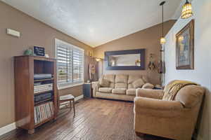 Living room featuring lofted ceiling, wood finished floors, and baseboards