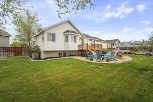 Back of property featuring a lawn, a deck, a patio area, and fence