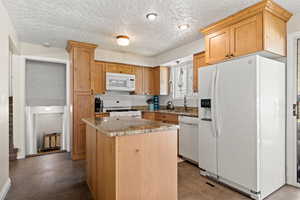 Kitchen with Alder cabinets, granite counters, a kitchen island, and white appliances.