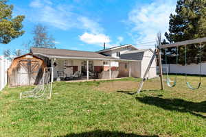Rear view of house featuring a fenced backyard, a yard, an outbuilding, a patio area, and a shed