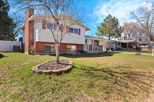 Tri-level home with fence, a chimney, a front yard, brick and  siding