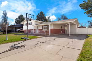 View of front of property featuring brick, siding, fence, a carport, driveway, and a front lawn