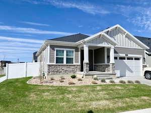 Craftsman inspired home featuring fence, concrete driveway, an attached garage, board and batten siding, and a front yard