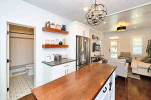 Kitchen with an inviting chandelier, recessed lighting, open shelves, island with wooden counters.